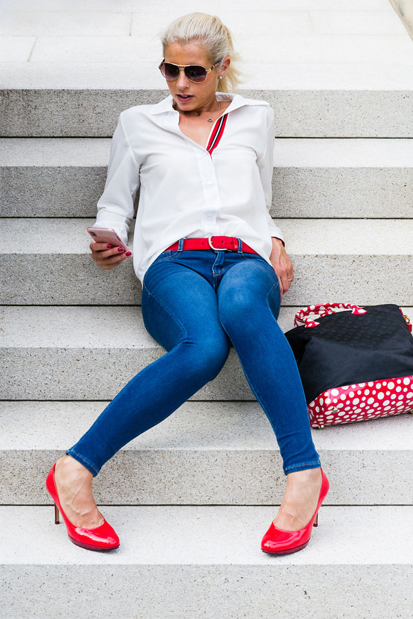 hot girl sitting on stairs with blue jeans and cool red shoes and red belt wearing sun glasses